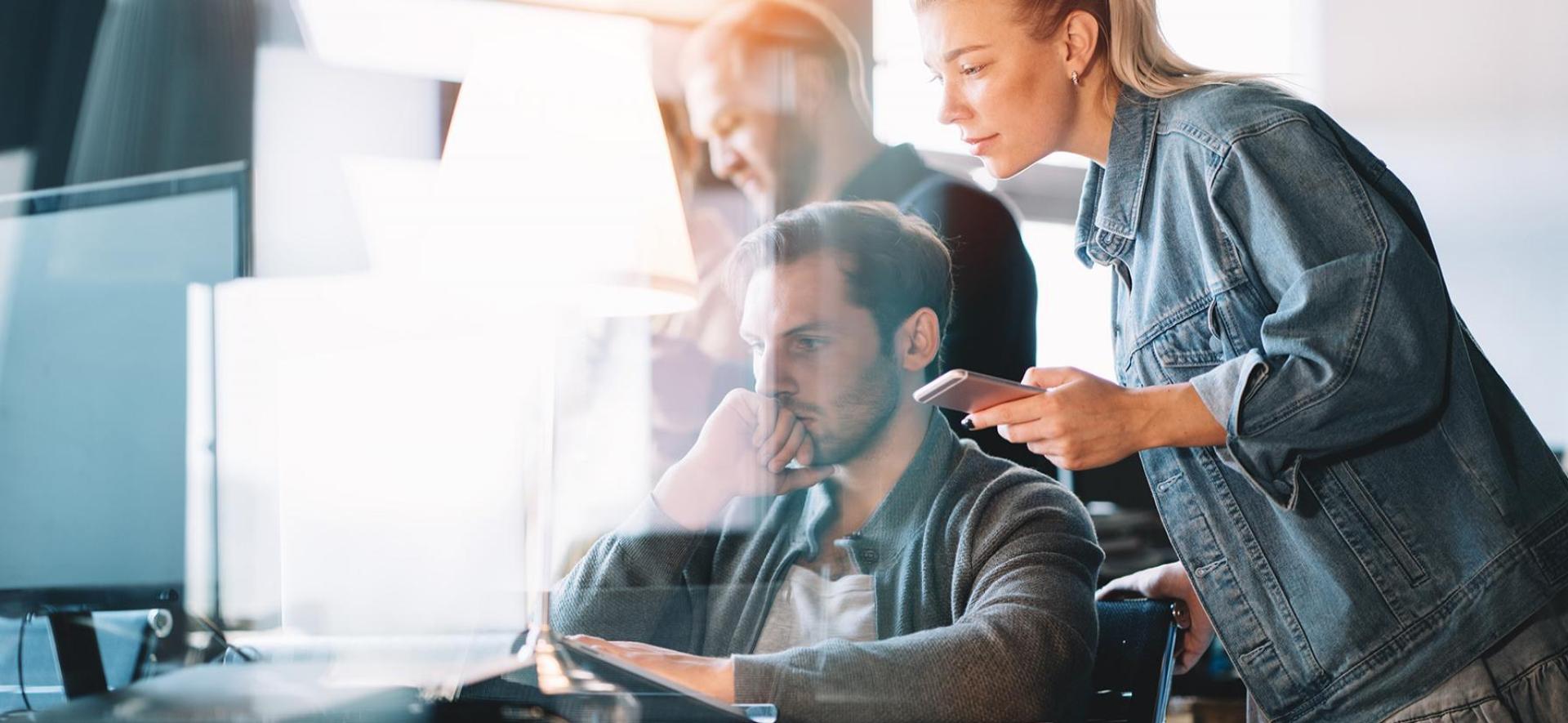 Grupa osób stojąca przy komputerze i patrząca na jego ekran