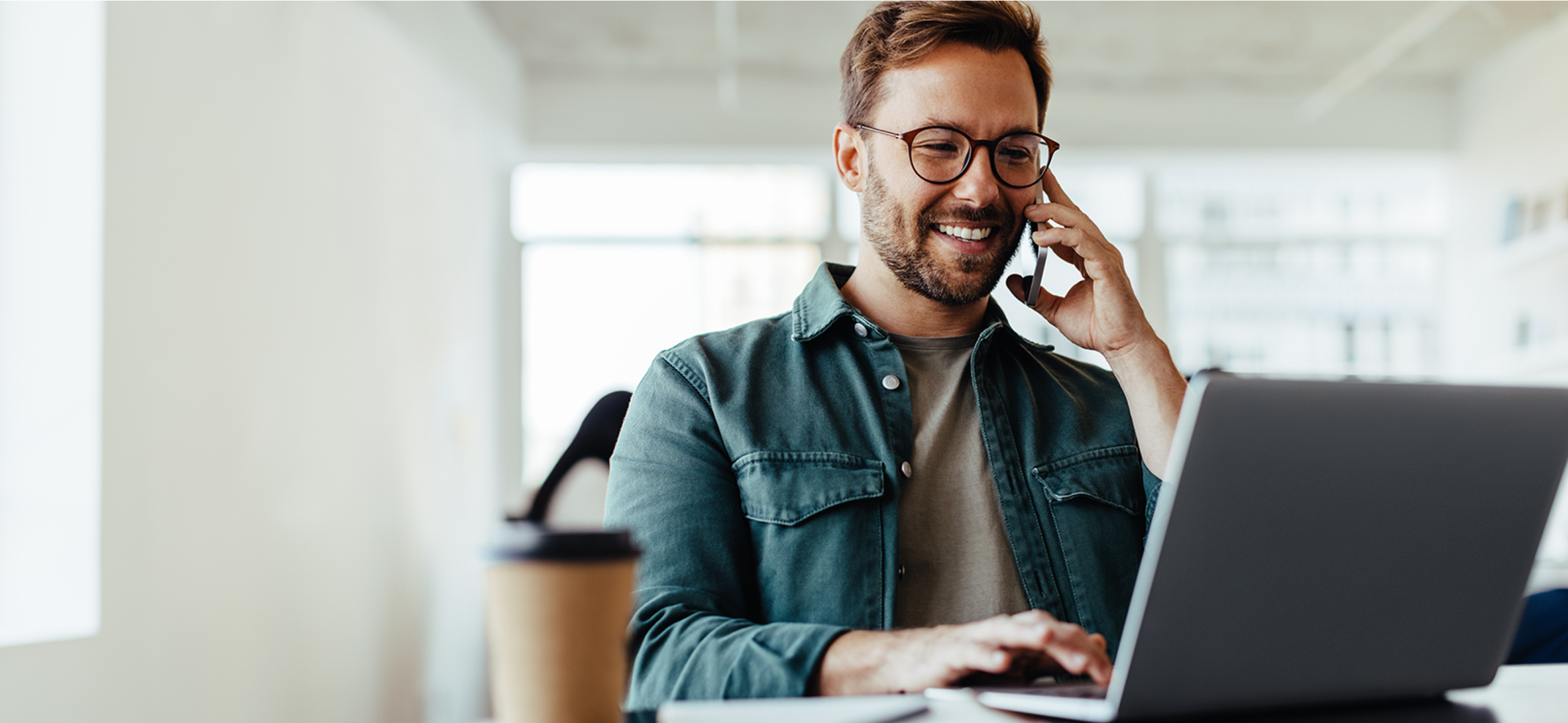 pracownik rozmawiający przez telefon przy komputerze