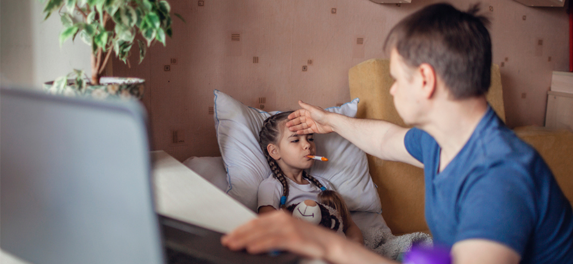 rodzic opiekujący się chorym dzieckiem. Dziecko leży, a tata sprawdza mu temperaturę.