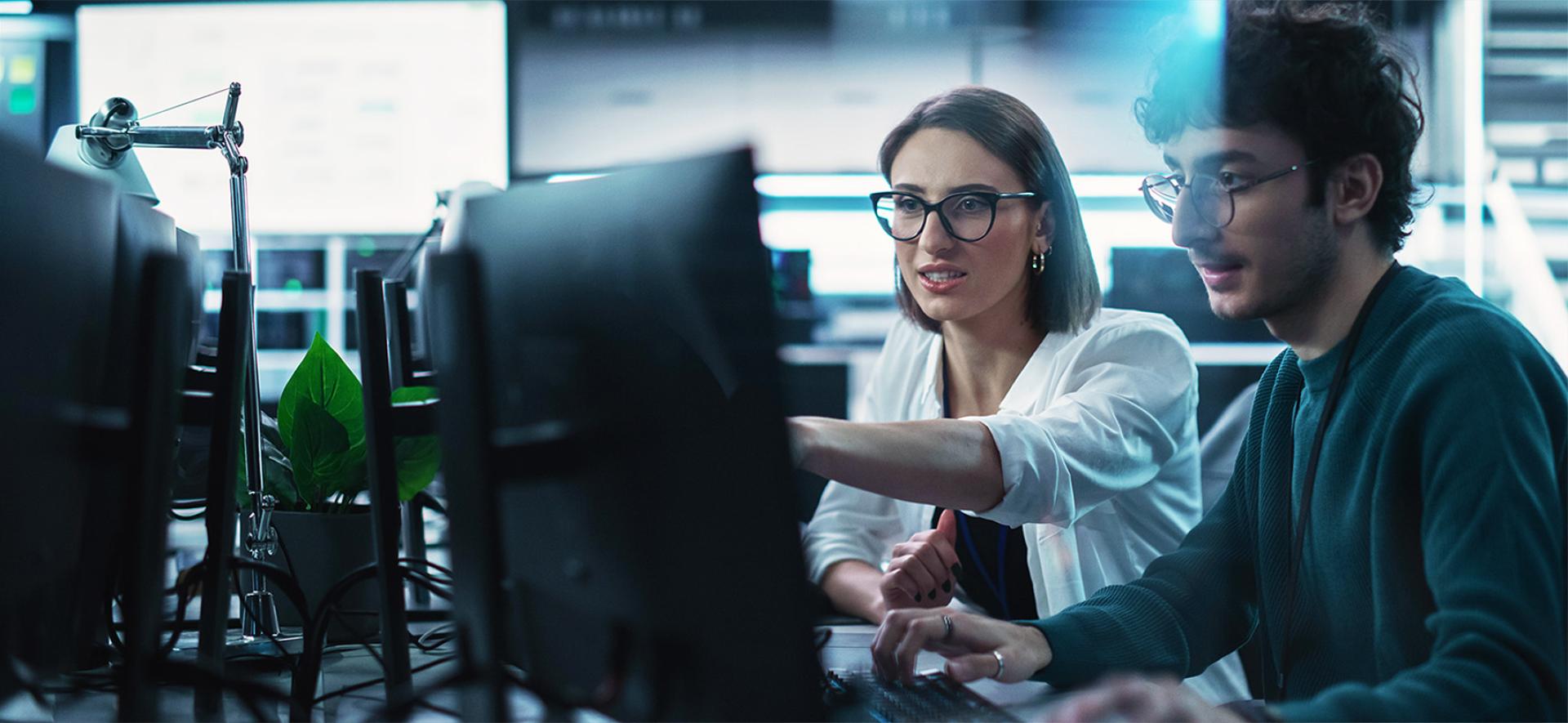 kobieta pokazuje mężczyźnie coś na monitorze, na który się patrzą