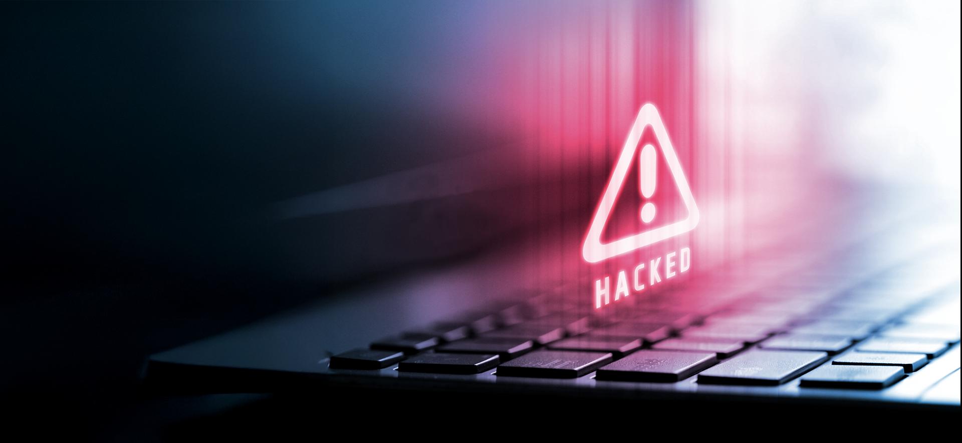 czerwony trójkąt z wykrzyknikiem w środku unosi się nad klawiaturą laptopa