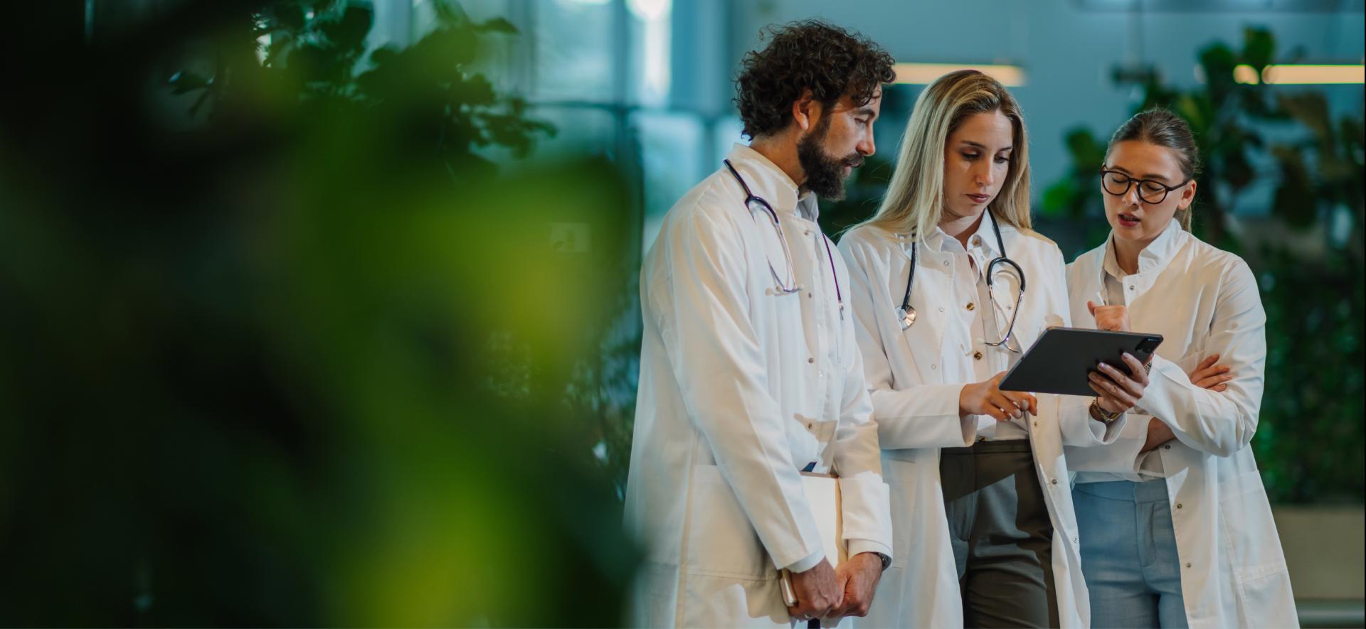 trzy osoby w kitlach lekarskich stoją i ze sobą rozmawiają