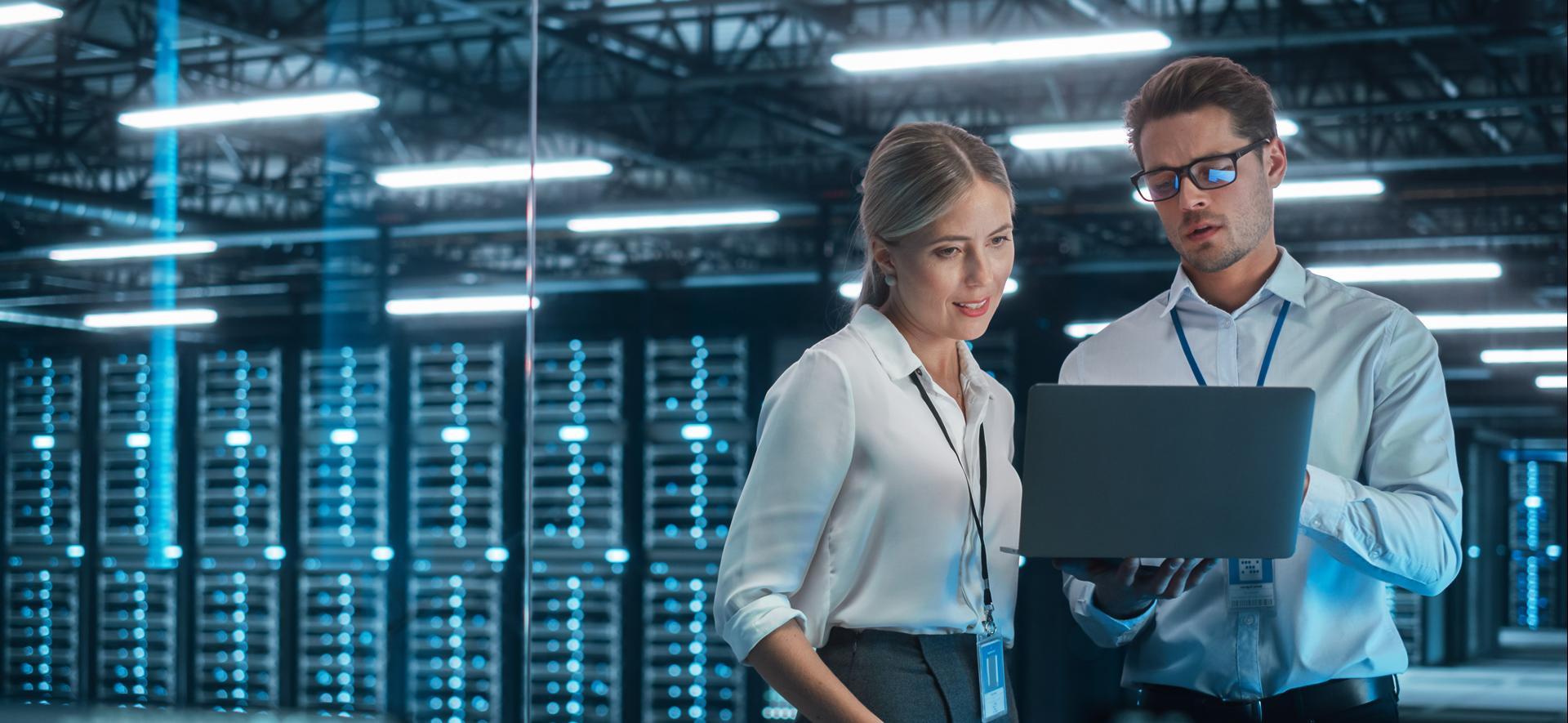 kobieta i mężczyzna ubrani w białe koszule patrzą na ekran laptopa