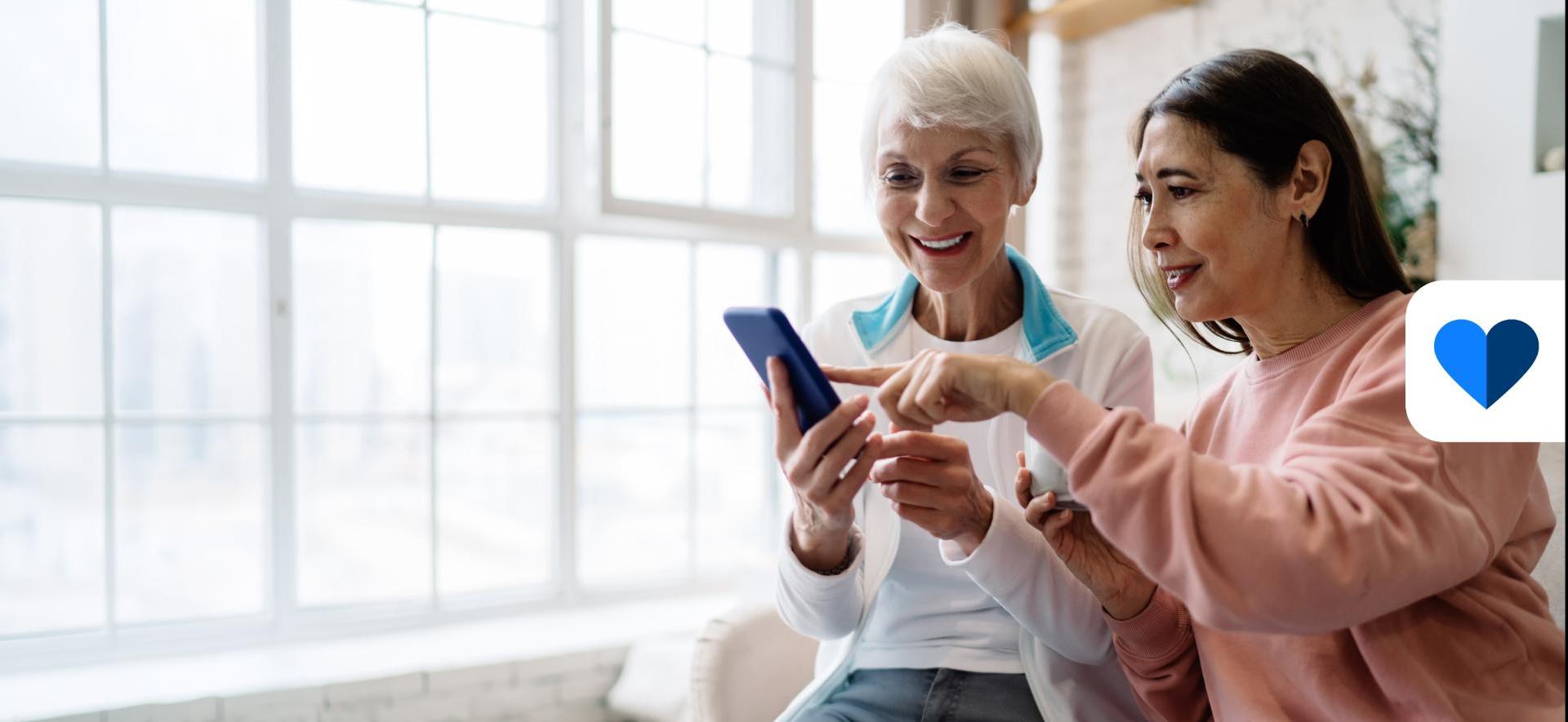 dwie kobiety patrzą na ekran smartfona