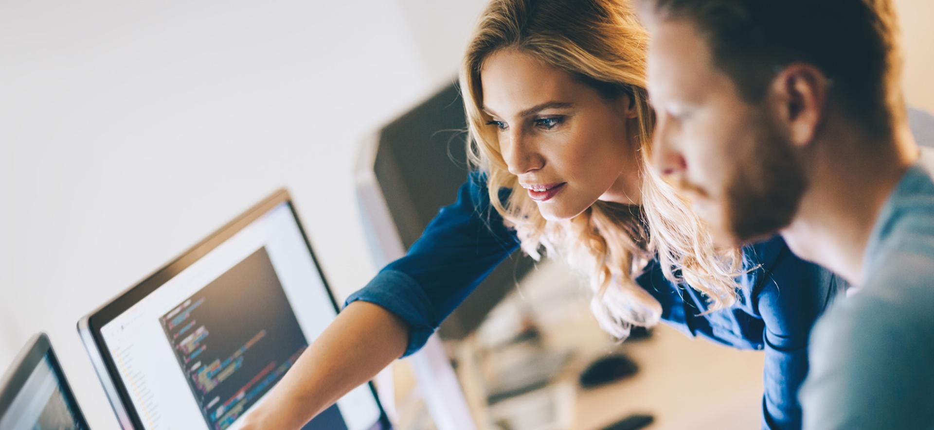 pracownik wskazujący drugiemu pracownikowi coś na ekranie komputera