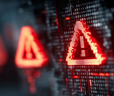 czerwony trójkąt z wykrzyknikiem w środku unosi się nad klawiaturą laptopa