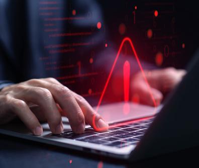 czerwony trójkąt z wykrzyknikiem w środku unosi się nad klawiaturą laptopa