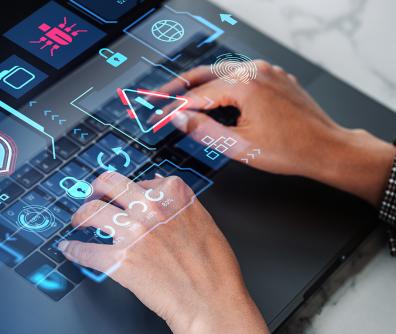 ręce na klawiaturze i czerwono niebieski trójkąt z wykrzyknikiem w środku