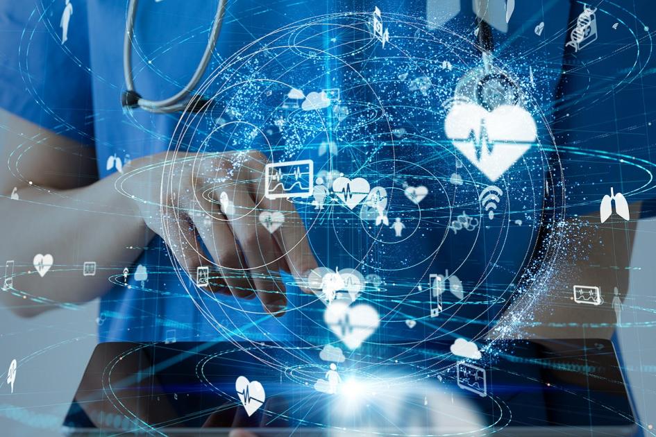 lekarz z tabletem w ręku, wokół wyświetlają się wirtualne ikony przedstawiające usługi e-zdrowia