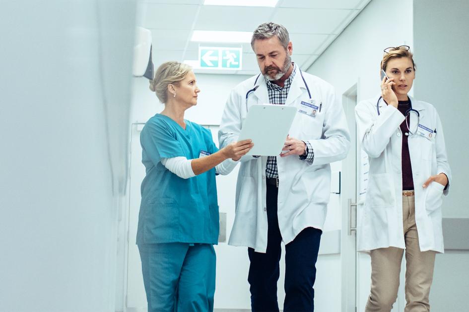 pielęgniarka, lekarz i lekarka rozmawiają, stojąc na korytarzu