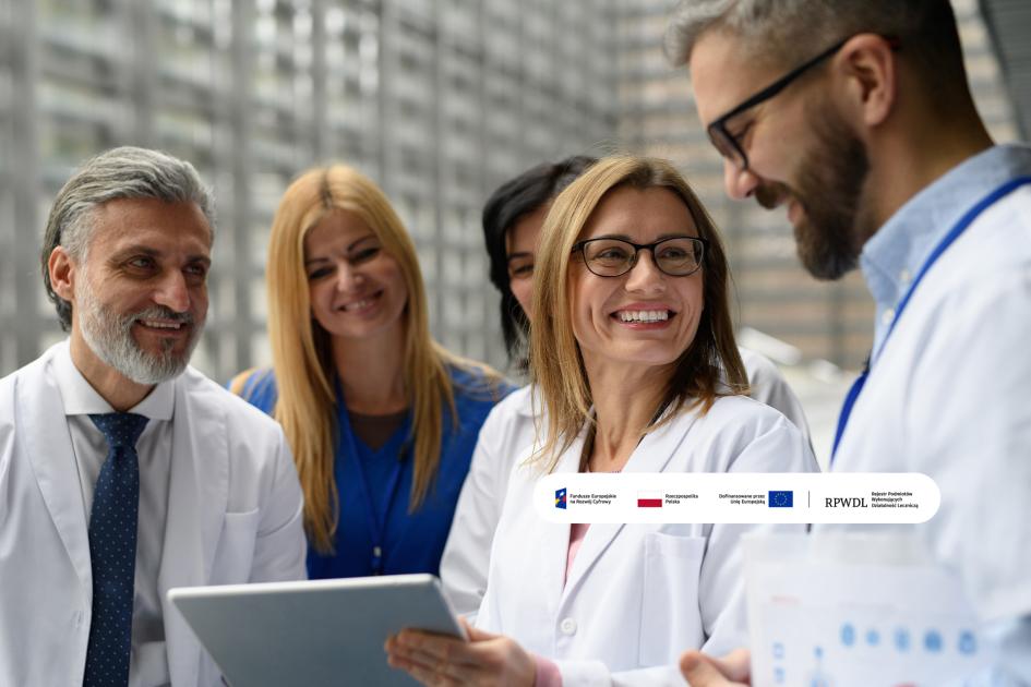 medycy patrzą się na ekran tabletu i uśmiechają się do siebie